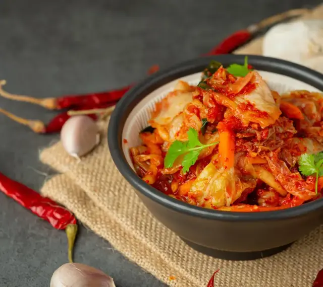 Miseczka z kimchi, obok suszone papryczki chili i czosnek.
